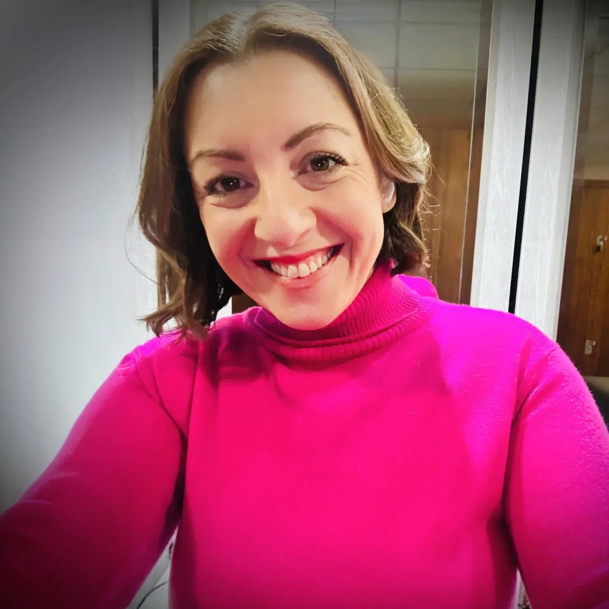 Katie Litchfield smiling after becoming a Top 100 Influential Person, wearing a pink top.